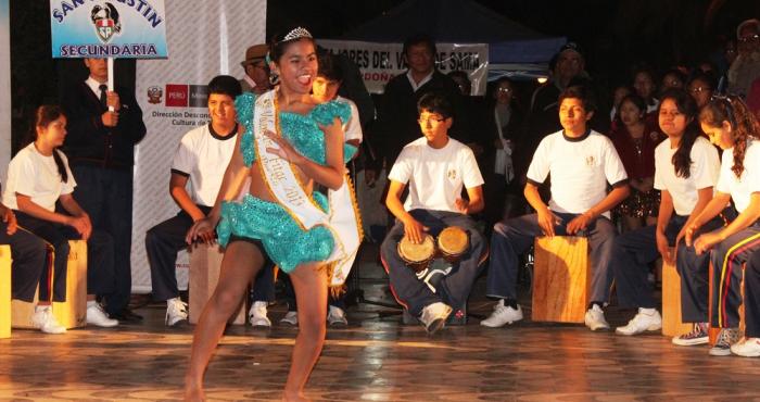 En la imagen se ve una niña afroperuana bailando y detrás de ella un grupo de niños que tocan cajón.