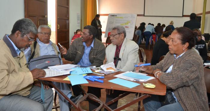 En la imagen se ve a cinco personas afroperuanas mayores, cuatro hombres y una mujer, alrededor de una mesa en una sesión de trabajo.